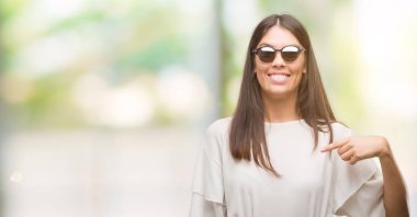 Genç güzel İspanyol sürpriz yüz işaret parmağı kendisi için güneş gözlüğü takıyor