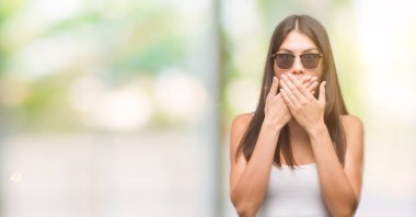 Genç güzel İspanyol ağız hata için elleriyle kapsayan şok güneş gözlüğü takıyor. Gizli kavramı.