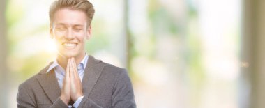 Yalvarıyor ve umut ifade yüzünde çok duygusal ve endişe ile birlikte elleriyle dua genç yakışıklı sarışın iş adamı. Bağışlanmak. Din kavramı.