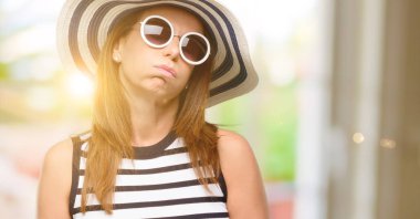 Orta yaş serin yaz şapka ve güneş gözlüğü ile aşırı ve yorgun uykulu ifade, giyen kadın