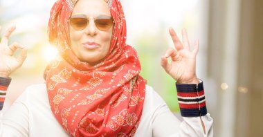 Meditasyon ve gevşeme ifade iki elinle ok işareti jest yapıyor hijab giyen orta yaş Müslüman Arap kadın