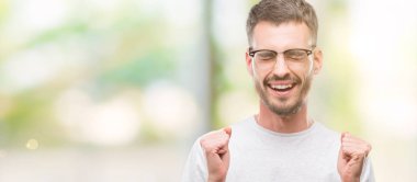 Zafer kutluyor gülümseyen genç dövmeli yetişkin adam silah ile başarı için heyecanlı kaldırdı. Kazanan kavramı.