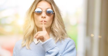 Genç güzel kadın ağzında, işaret parmağı ile smartphone kullanarak sormak sessiz olmalısın. Sessizlik ve gizli kavramı