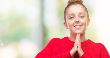 Bun ve kırmızı kazaklı ellerle birlikte AF emin gülümseyen için soran dua giyen genç sarışın kadın.