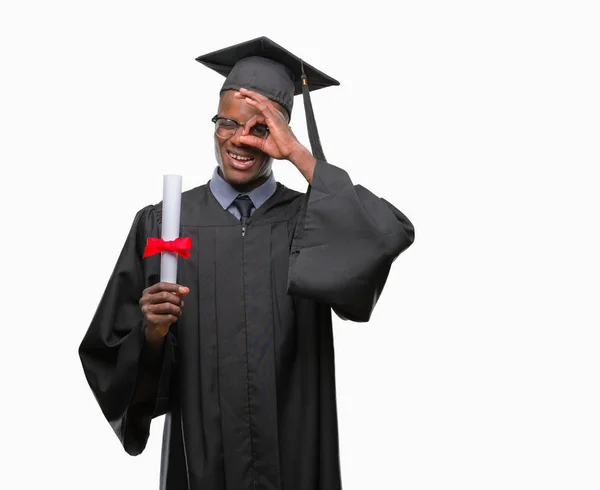 ヤングは 指を通して見る目に手で サインをして笑っている幸せそうな顔で孤立の背景の上の学位を保持するアフリカ系アメリカ人を卒業 — ストック写真