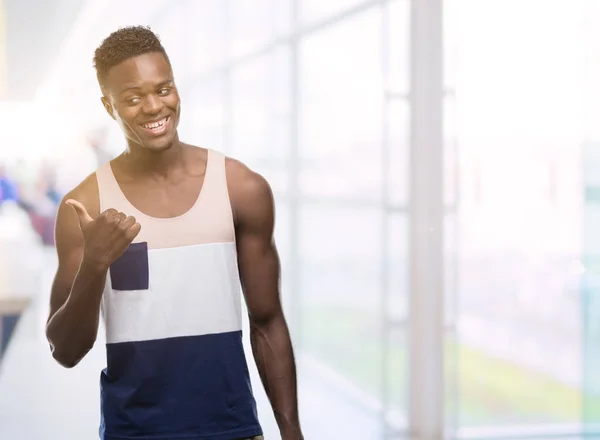 Young african american man pointing with hand and finger up with happy face smiling