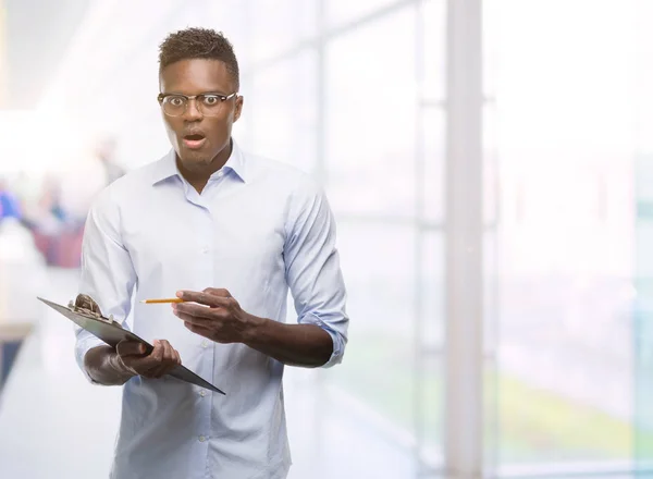 Jovem Afro Americano Segurando Uma Prancheta Assustada Choque Com Rosto — Fotografia de Stock