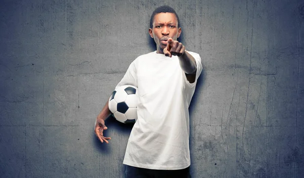 African black man holding soccer ball pointing to the front with finger