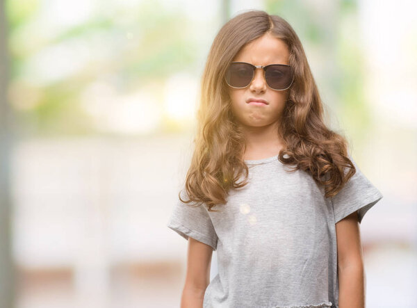 Брюнетка латиноамериканка в солнечных очках скептически и нервно, хмурясь расстроена из-за проблем. Отрицательное лицо
.