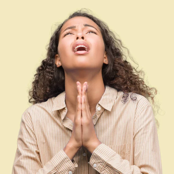 Young hispanic business woman begging and praying with hands together with hope expression on face very emotional and worried. Asking for forgiveness. Religion concept.