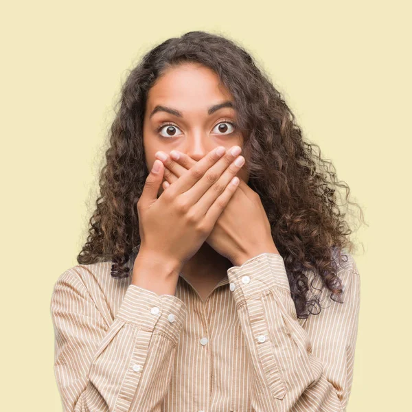 Young hispanic business woman shocked covering mouth with hands for mistake. Secret concept.