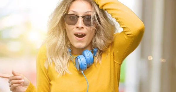 Mujer Hermosa Joven Con Auriculares Apuntando Hacia Lado Con Dedo — Foto de Stock