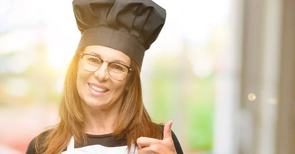 中年厨师妇女穿着厨师围裙微笑广泛显示大拇指向上手势相机 表达的喜欢和批准 — 图库照片
