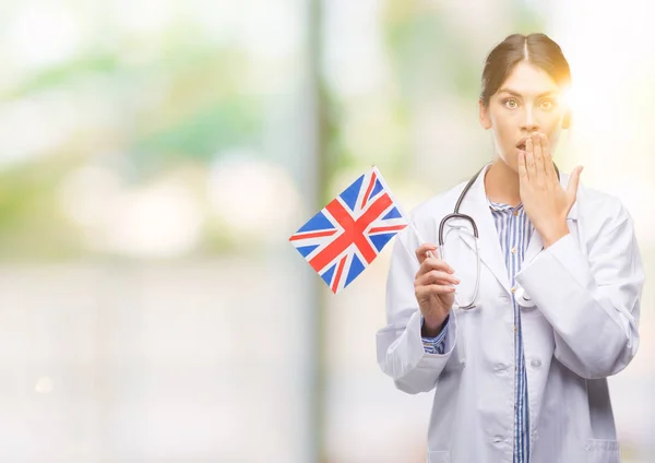 Jovem Médica Hispânica Segurando Bandeira Reino Unido Cobrir Boca Com — Fotografia de Stock