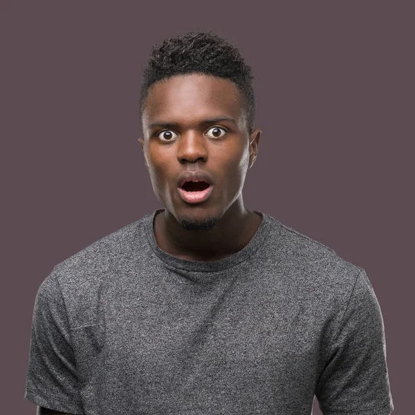 Korkuyor ve şok sürpriz ifade, korku ve heyecan yüz ile gri t-shirt giyen genç Afro-Amerikan adam.