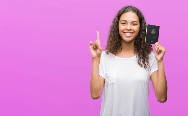 持有澳大利亚护照的年轻西班牙裔妇女惊讶于一个想法或问题 手指与快乐的脸 — 图库照片