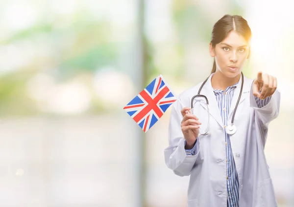Jovem Médica Hispânica Segurando Bandeira Reino Unido Apontando Com Dedo — Fotografia de Stock