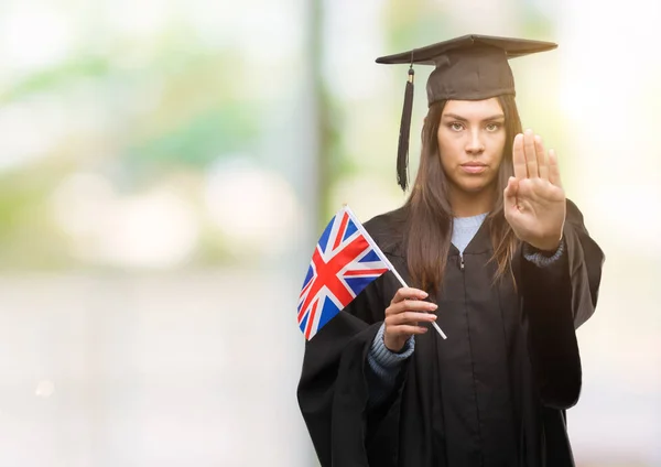 年轻的西班牙裔女子身穿统一的英国国旗用张开的手做停止标志以严肃和自信的表达 防御姿态 — 图库照片