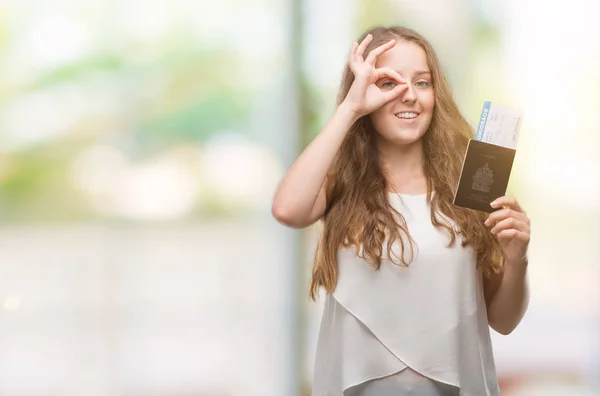 カナダと指を通して見る目に手で サインをして笑っている幸せそうな顔で搭乗券の若いブロンドの女性持株パスポート — ストック写真