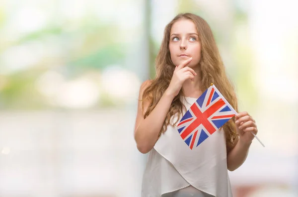 Unga Blonda Kvinnan Håller Flaggan Allvarligt Ansikte Funderar Frågan Mycket — Stockfoto