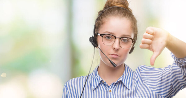Молодая блондинка оператор колл-центра женщина с сердитым лицом, негативный знак показывает неприязнь с опущенными пальцами, отвержение концепции
