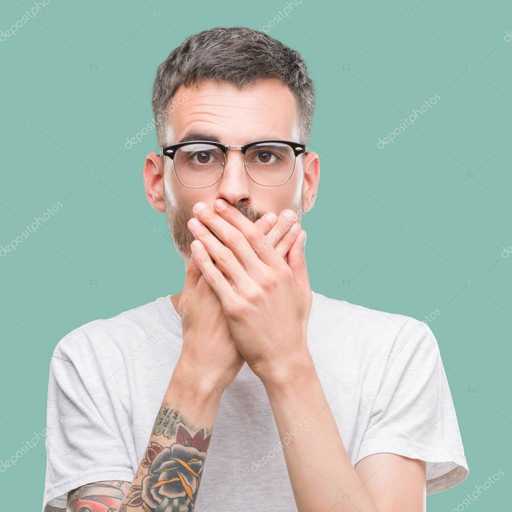Young tattooed adult man shocked covering mouth with hands for mistake. Secret concept.