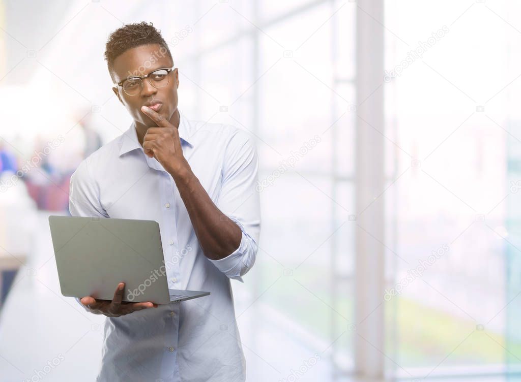 Young african american businessman using computer laptop serious face thinking about question, very confused idea
