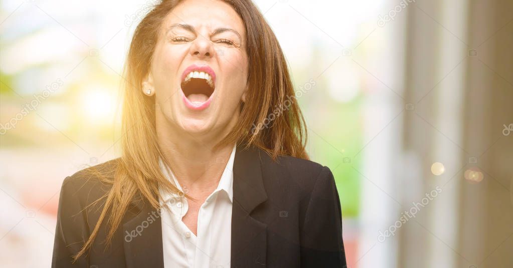 Middle age woman wearing jacket stressful, terrified in panic, shouting exasperated and frustrated. Unpleasant gesture. Annoying work drives me crazy