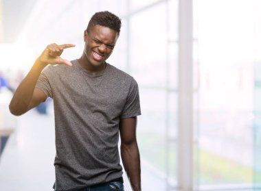 Genç Afro-Amerikan adam giyen gri gömlek gülümseyen ve boyutu işi el ile kendinden emin eller parmakları ile seyir ve fotoğraf makinesi oturum açın. Ölçü kavramı.