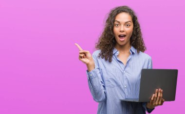 Bilgisayar dizüstü çok mutlu el ve parmak ile tarafına işaret tutan genç İspanyol kadın