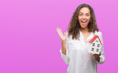 Yazlık çok mutlu ve heyecanlı, kazanan ifade ile çığlık zaferini kutluyor büyük tutan genç İspanyol gerçek durum Aracısı kadın gülümse ve el kaldırdı