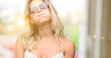 Genç kadın kalp şeklinde uykulu ifade, çok çalıştırılıyordu ve yorgun ile güneş gözlüğü takıyor