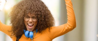 Büyük başarı, güç, enerji ve olumlu duygular ifade Afro-Amerikan öğrenci kadın mutlu ve heyecanlı kutluyor zafer. Yeni iş neşeli kutluyor