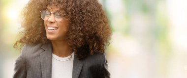 Afro-Amerikan iş kadını uzak tarafına yüzünde, doğal ifade gülümseme ile seyir gözlük takıyorum. Kendine güvenen gülüyor.