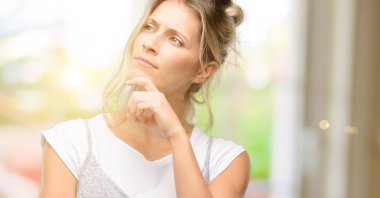 Genç, güzel bir kadın, düşünüyor, yukarı bakıyor şüphe ve merakını dile getiriyor.