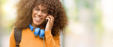 Afrika kökenli Amerikalı öğrenci kadın bir smartphone cep telefonu kullanarak konuşmak mutlu