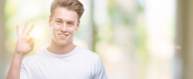 Parmak, mükemmel sembolü ile ok işareti yapan genç yakışıklı sarışın erkek