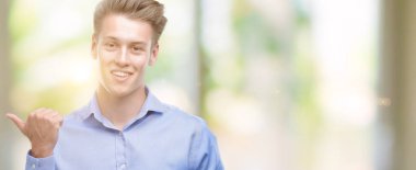 El ve parmak ile yukarı dönük mutlu yüz gülümseyen ile akıllı telefon kullanan genç yakışıklı sarışın adam