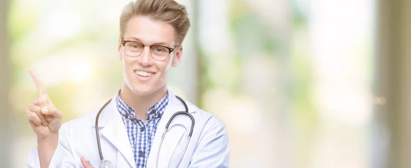 Young Handsome Blond Doctor Very Happy Pointing Hand Finger Side — Stock Photo, Image