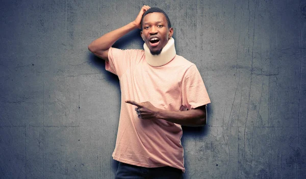 Injured african black man wearing neck brace pointing away side with finger