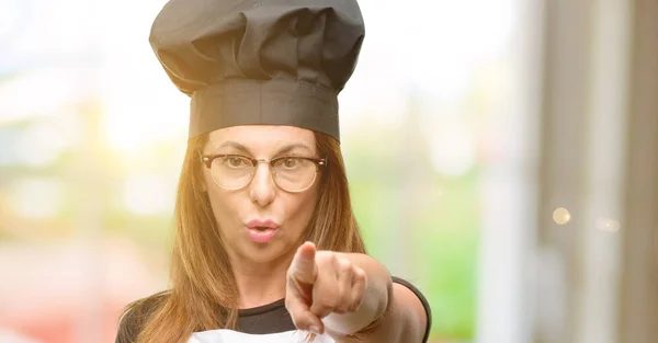 中年厨师妇女穿着厨师围裙指向前面用手指 — 图库照片