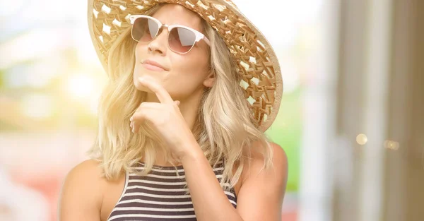Jovem Mulher Usando Óculos Sol Usando Chapéu Verão Pensando Olhando — Fotografia de Stock