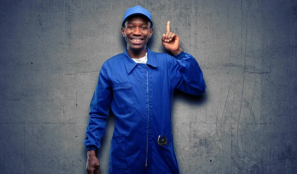 African black plumber man happy and surprised cheering expressing wow gesture pointing up