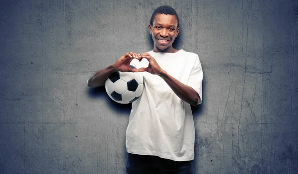African black man holding soccer ball happy showing love with hands in heart shape expressing healthy and marriage symbol