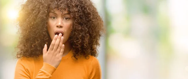African american woman with a pizza slice cover mouth with hand shocked with shame for mistake, expression of fear, scared in silence, secret concept