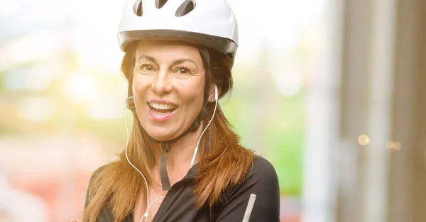 Donna Ciclista Mezza Età Utilizzando Auricolari Che Tengono Qualcosa Mano — Foto Stock