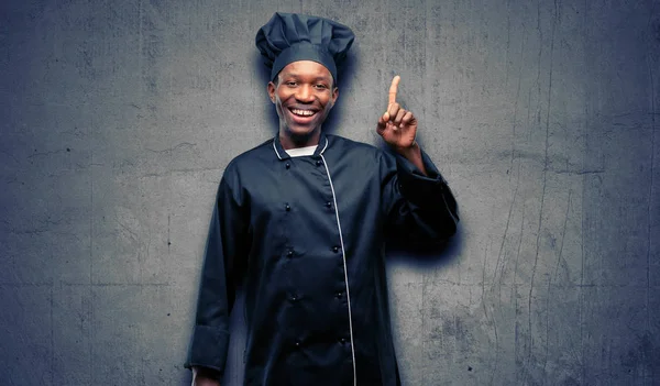 年轻的黑人厨师戴着主厨帽指着一边用手指 — 图库照片