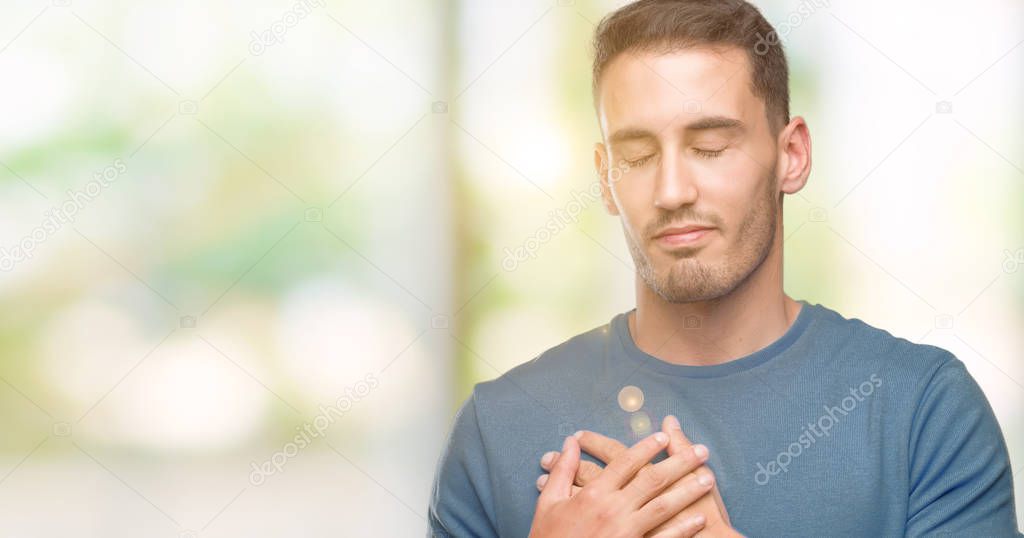 Handsome young casual man smiling with hands on chest with closed eyes and grateful gesture on face. Health concept.