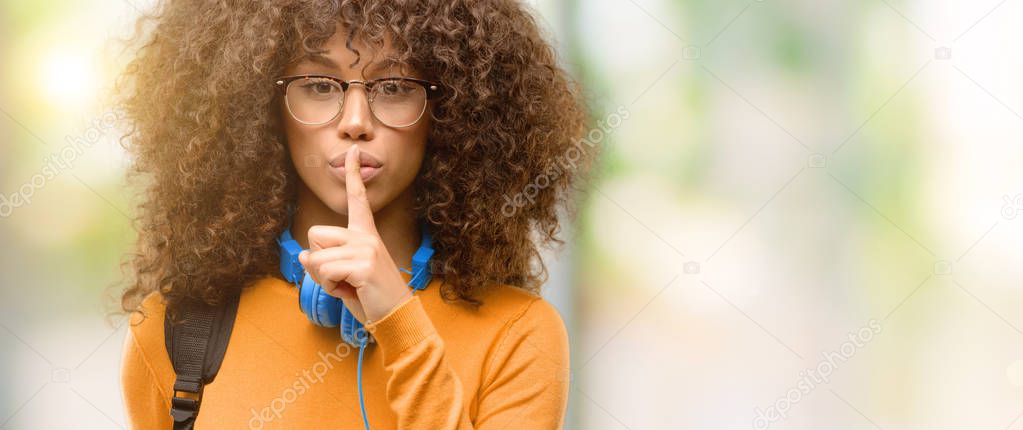 African american student woman with index finger on lips, ask to be quiet. Silence and secret concept