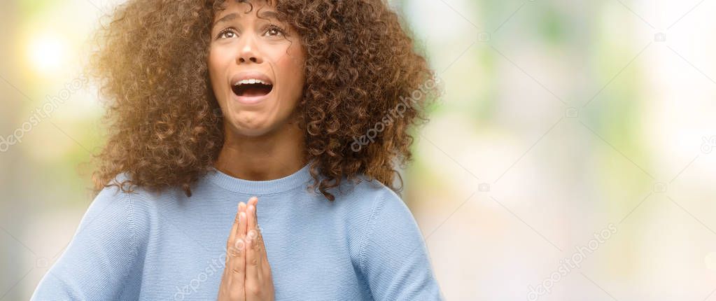 African american woman wearing a sweater begging and praying with hands together with hope expression on face very emotional and worried. Asking for forgiveness. Religion concept.
